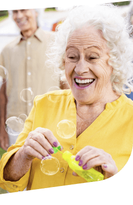 Joyful Elderly Woman Laughing While Blowing Bubbles Outdoors in Independent Living Joyful Elderly Woman Laughing While Blowing Bubbles Outdoors in Independent Living