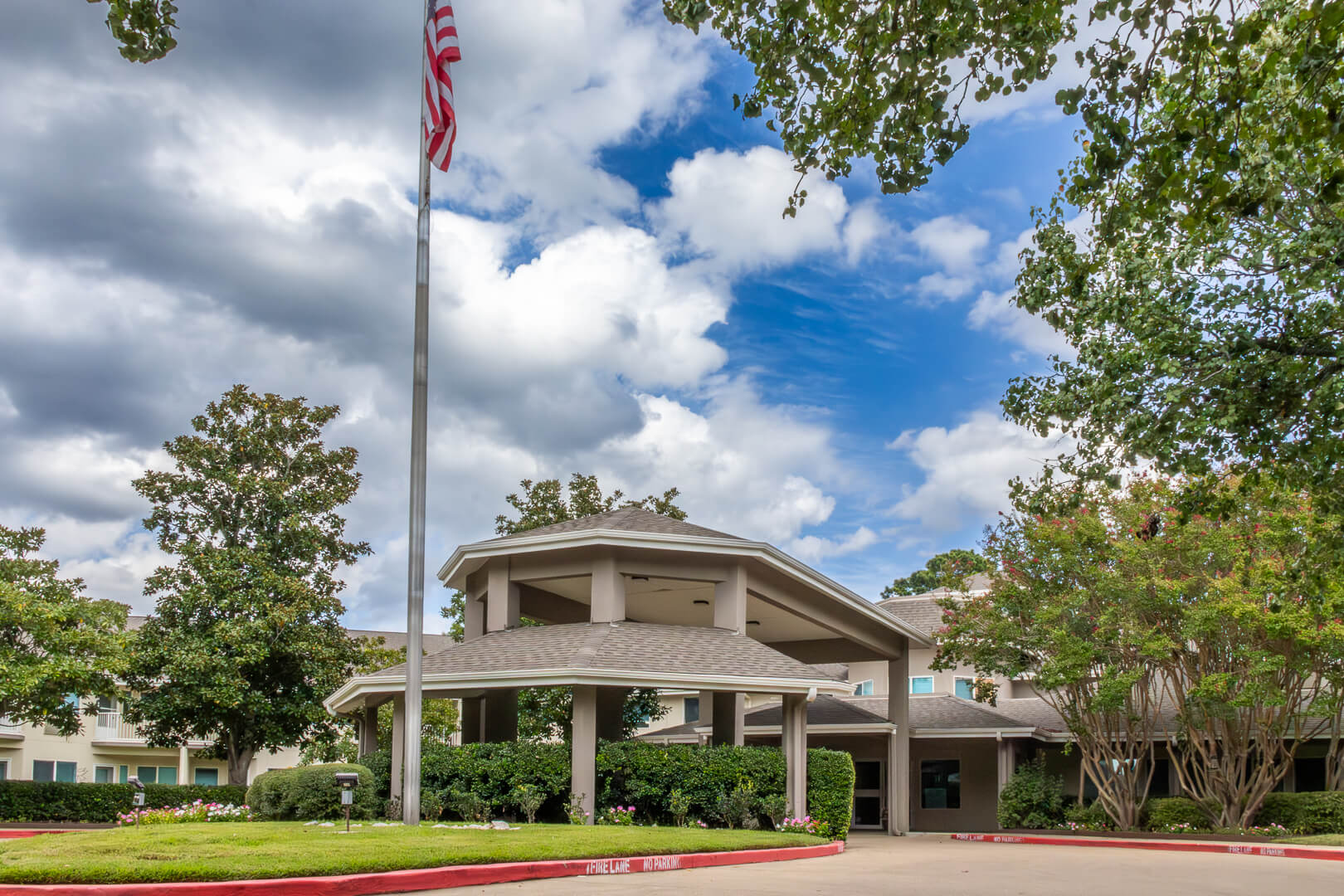 Covered Entrance with American Flag and Landscaped Grounds at an Independent Living Community