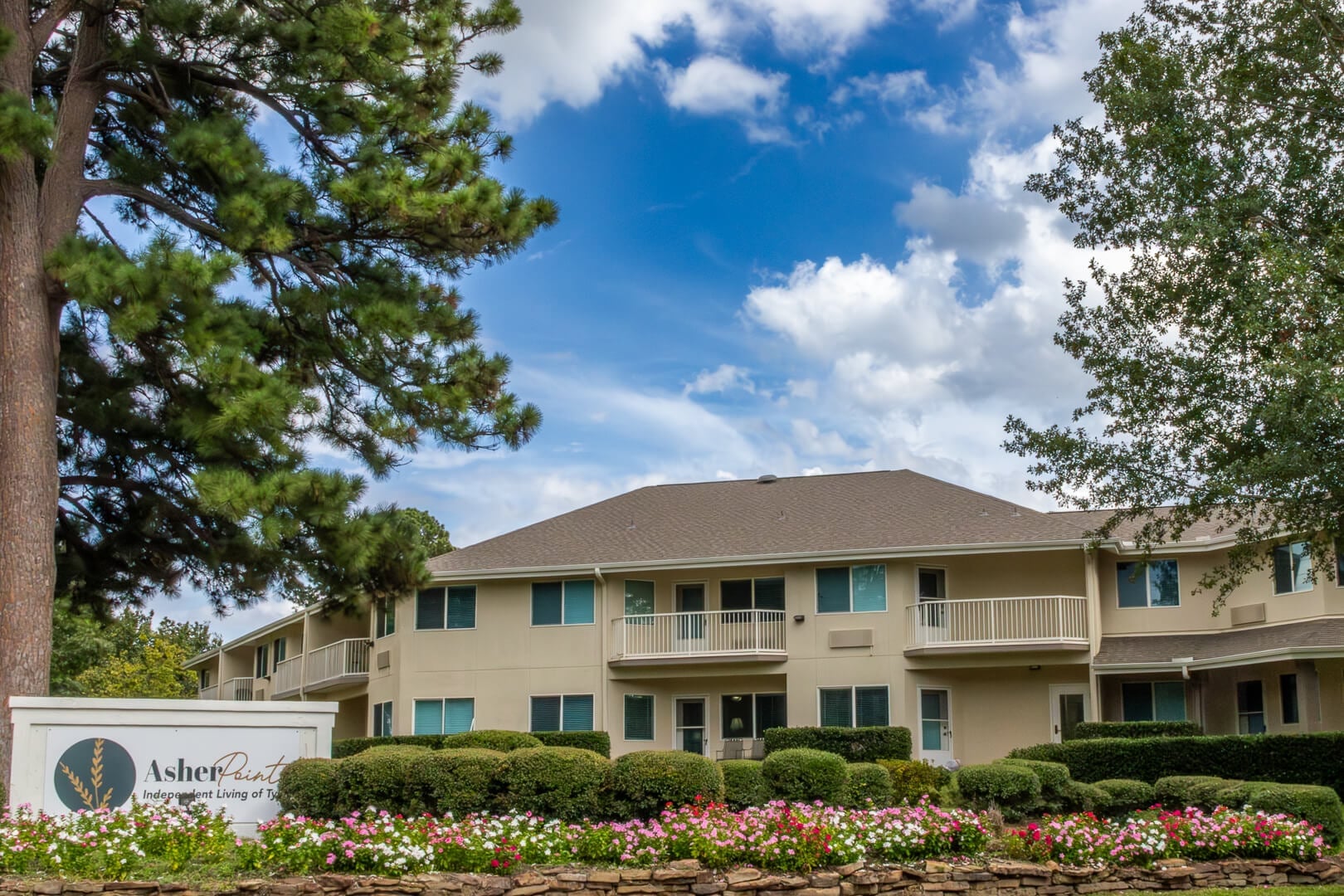 Asher Point Exterior with Mature Trees and Blooming Flower Beds at an Independent Living Community