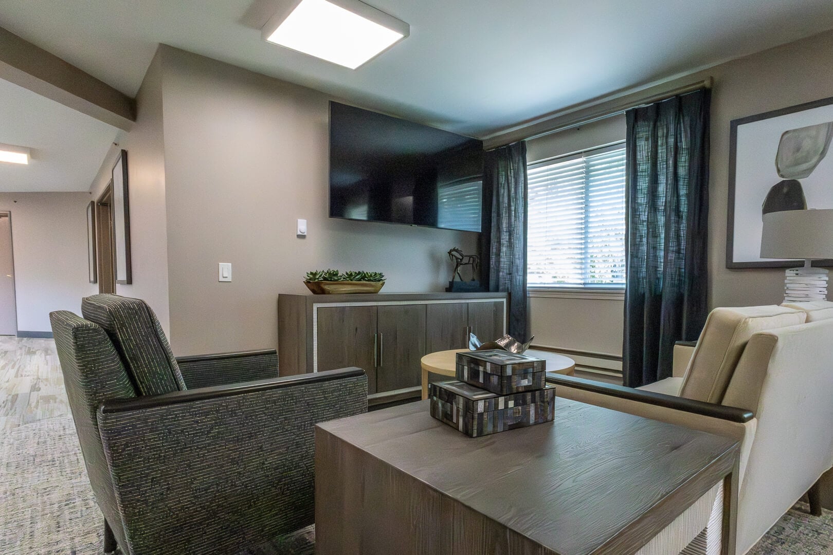 Cozy Resident Sitting Room with TV and Curtained Windows at an Independent Living Facility